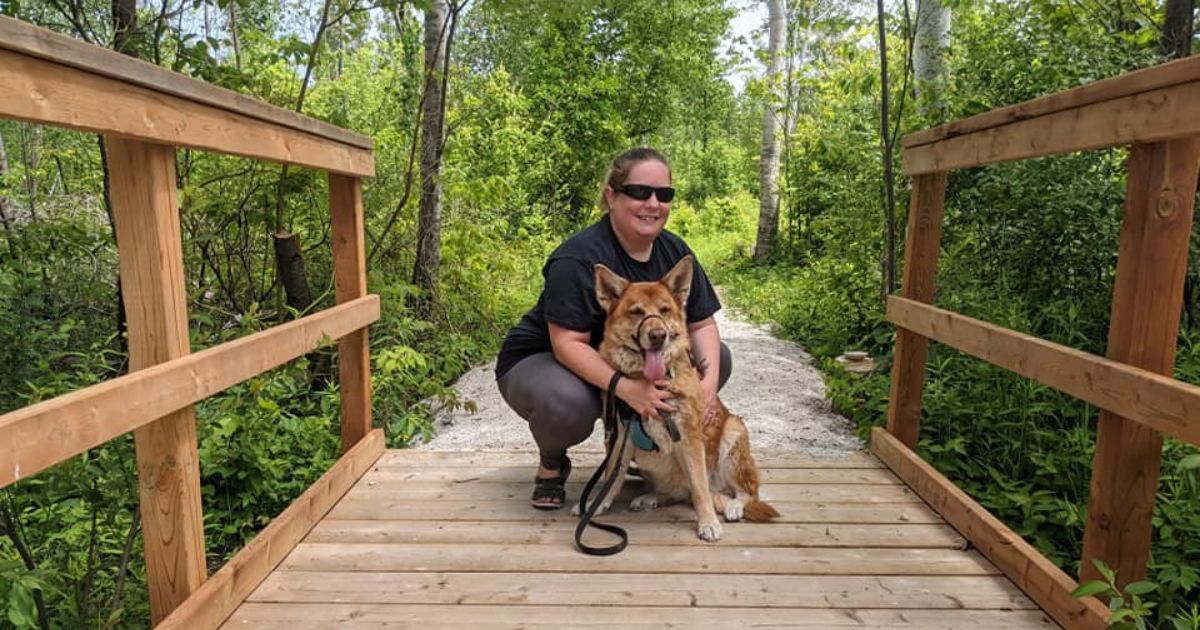 woman crouched on wooden walkway with dog | Dog-Friendly Ontario Parks Roofed Accommodations