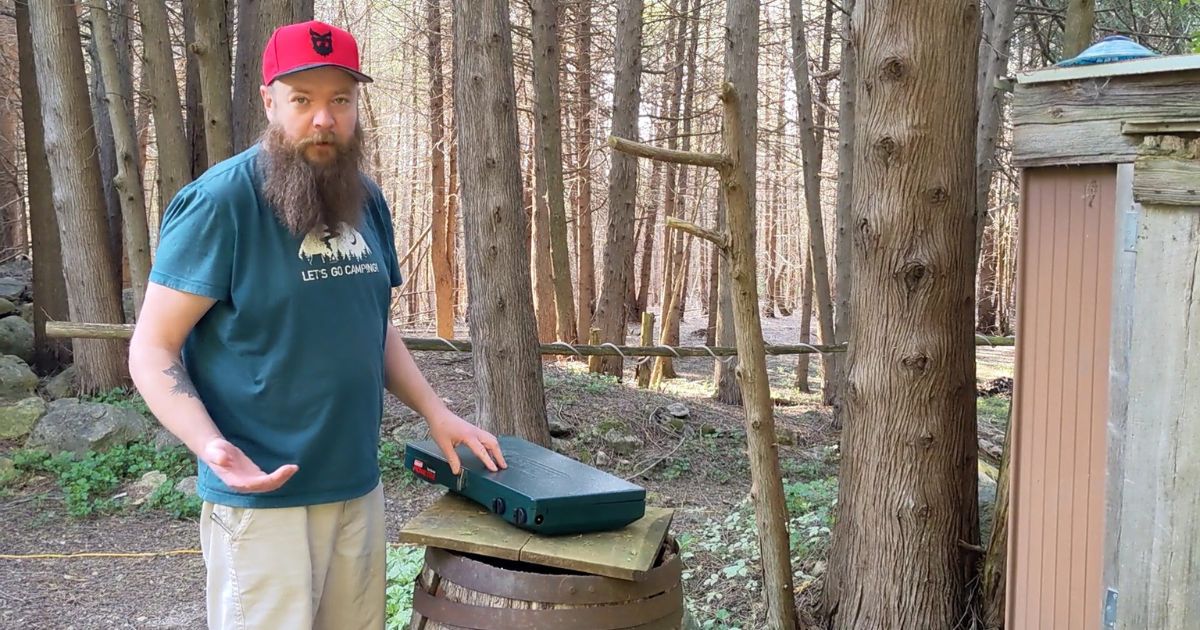 man standing next to a propane camp stove | Get Ready for Camping Like a Pro